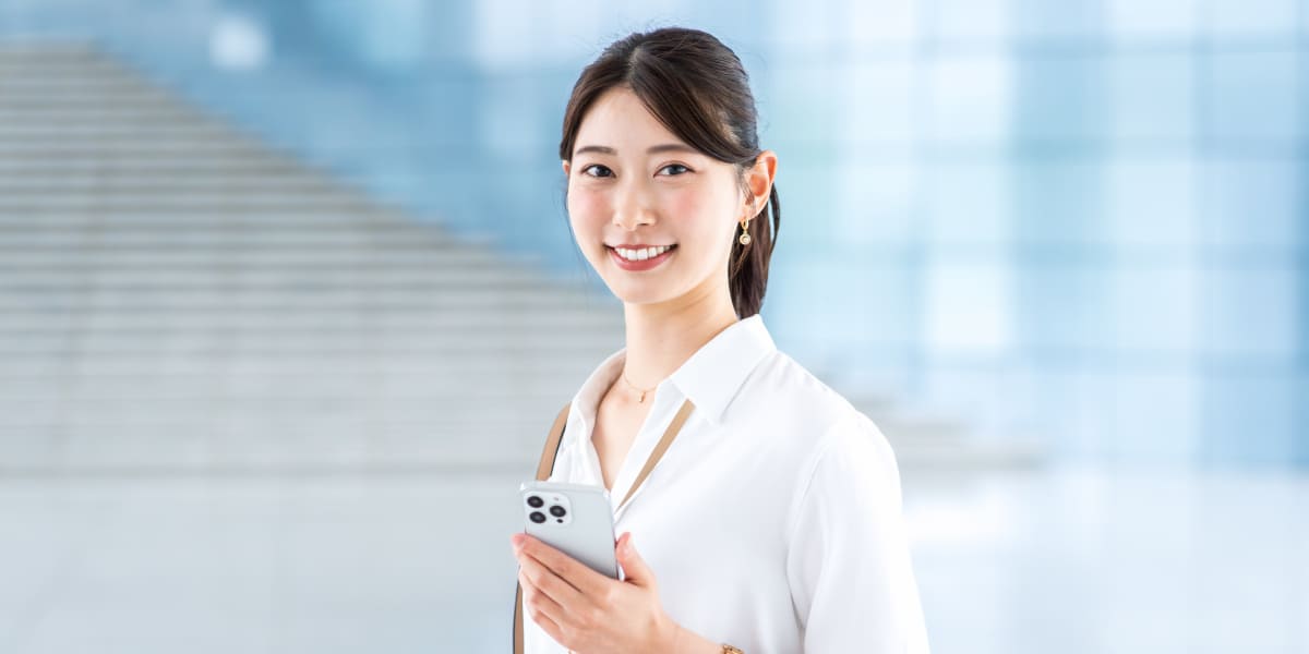 スマホを持ち微笑む人物の画像
